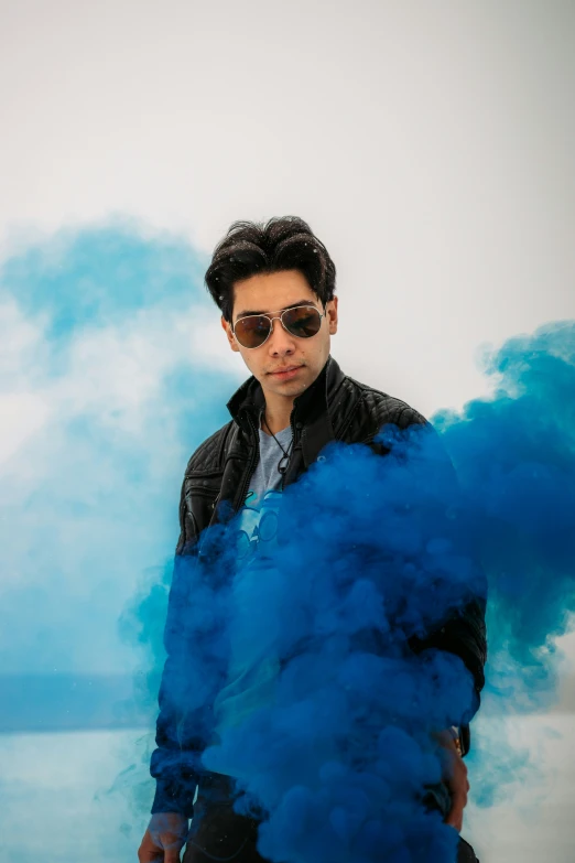 a man wearing sunglasses with blue smoke coming out of his jacket