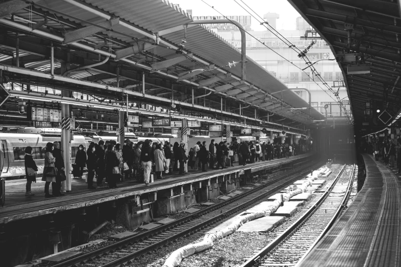 a train station with people standing in the train tracks