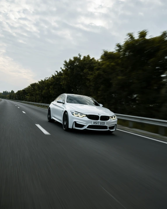 the white sports car is traveling on the highway