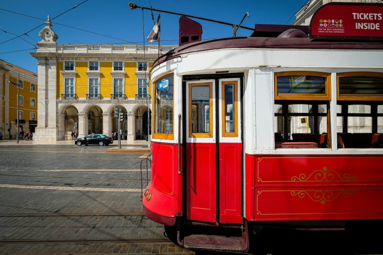 red and white trolley car traveling through city streets