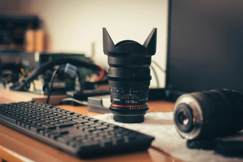 an empty camera lens sitting next to a computer