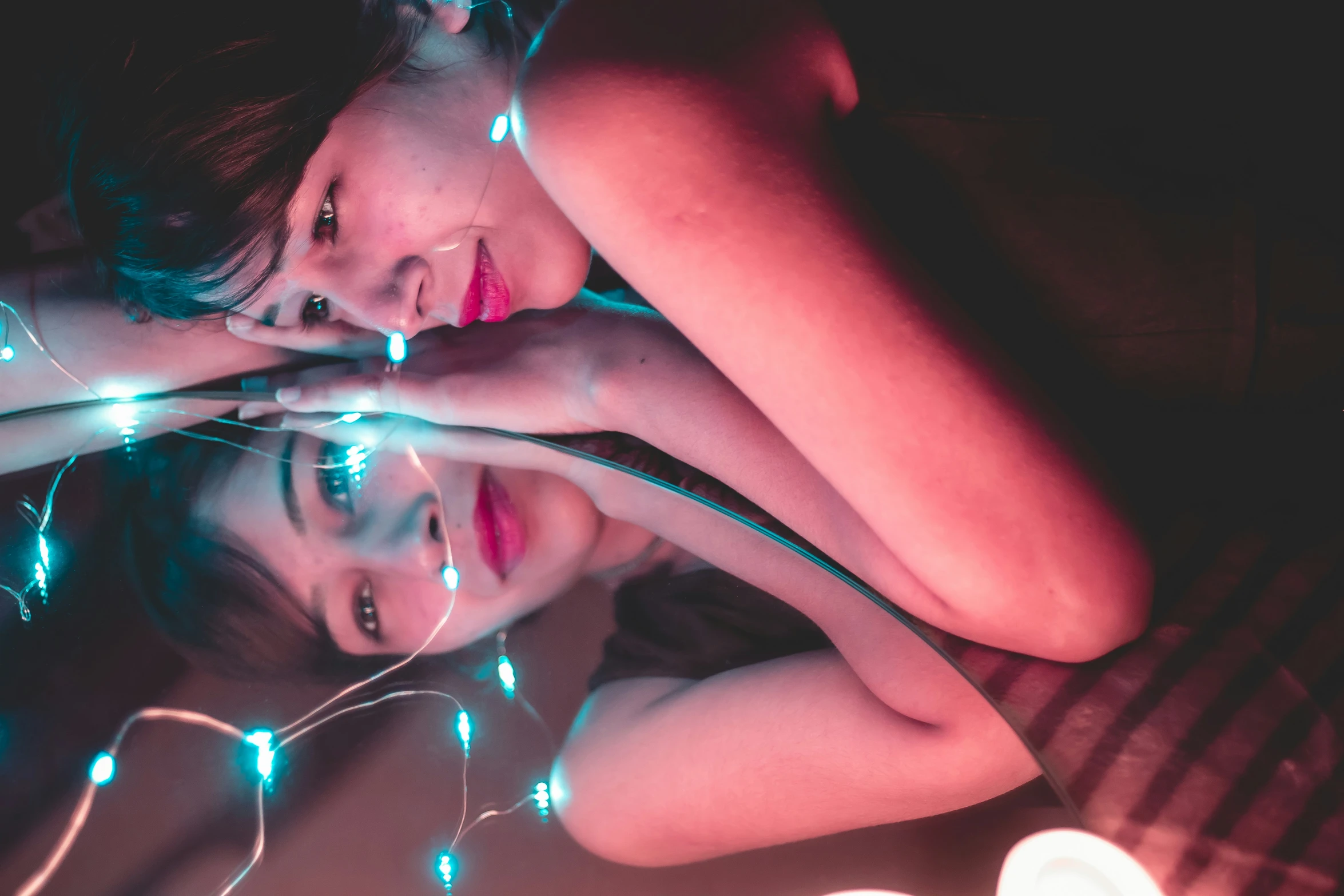 two girls laying next to each other on top of a bed