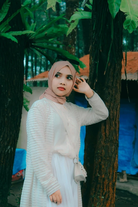 a woman is standing next to a tree