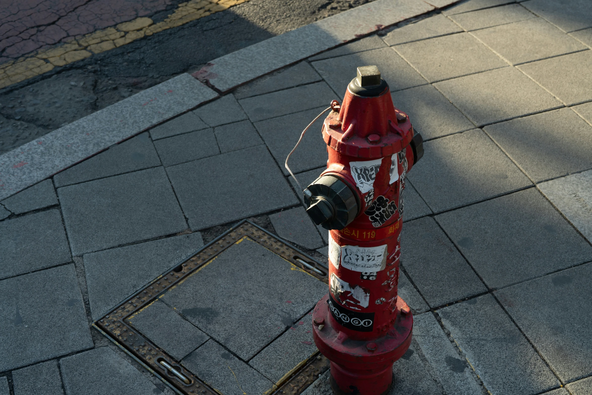 a red fire hydrant sitting next to a metal grate on the side of a road