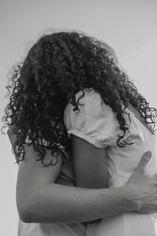 a man hugs a woman who is covering her face
