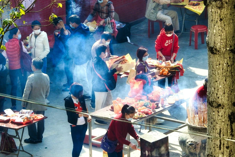 group of people gathered around a wooden table with smoke coming out