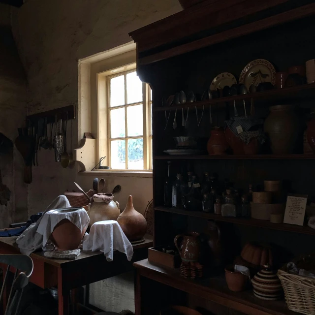 a table topped with plates and vases under a window