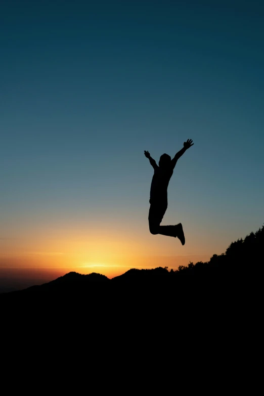 a silhouette of a person jumping in the air