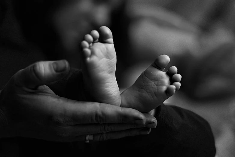 the fingers of the person hold a small baby's foot