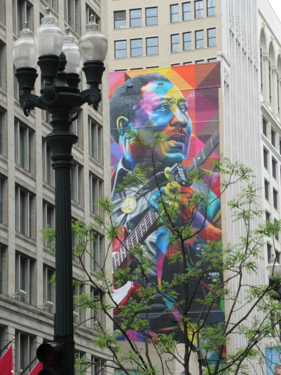 a large mural of a man playing guitar is displayed on the side of a building