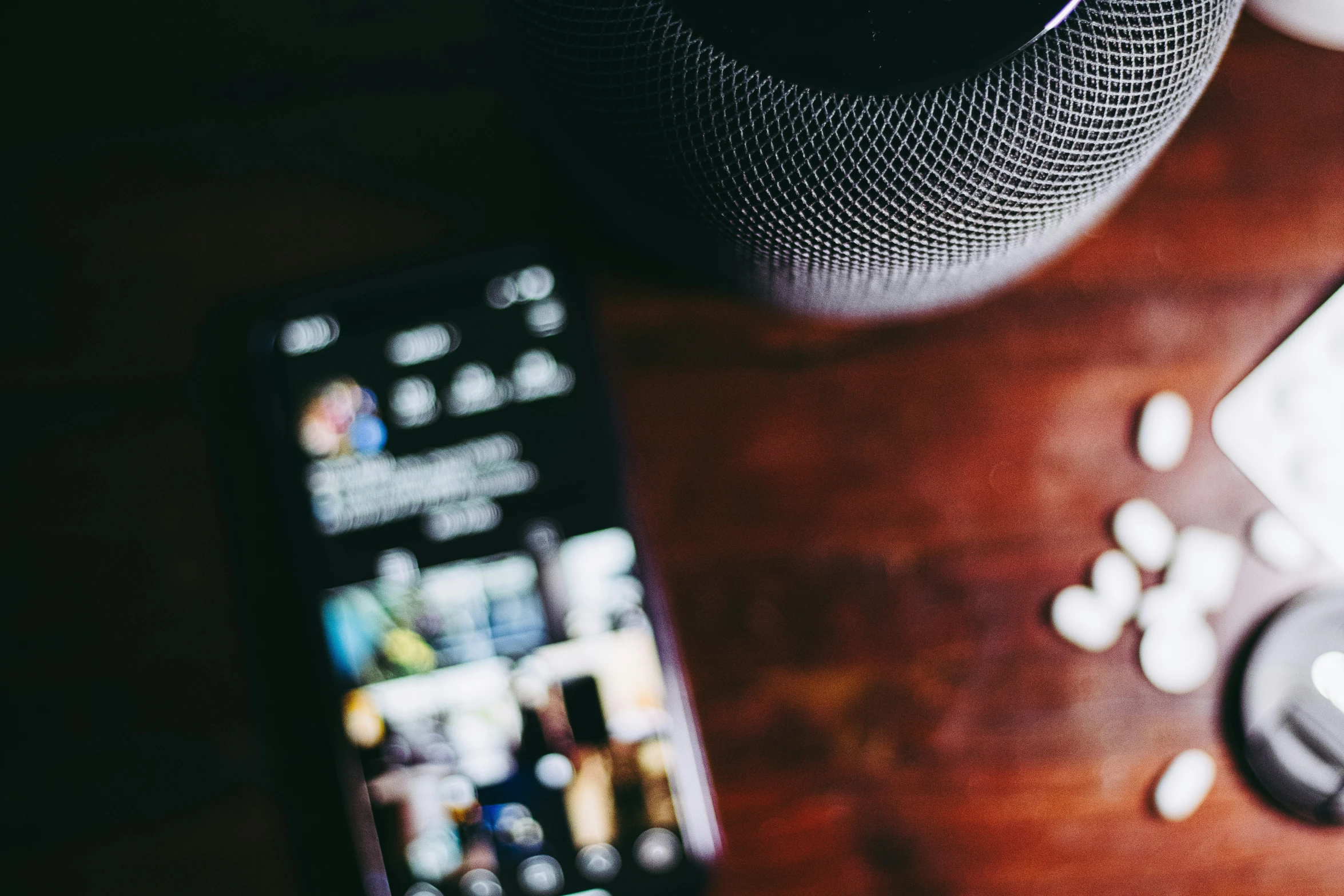 a phone sitting on top of a wooden desk next to a speaker