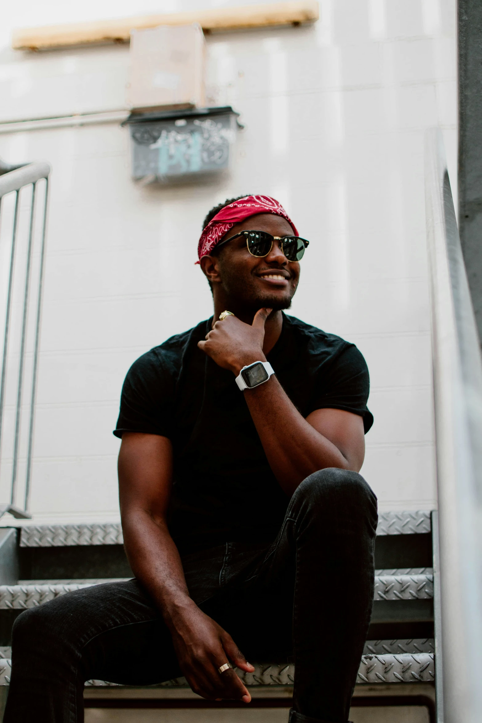 a man wearing sunglasses and a pink bandana sitting on the steps