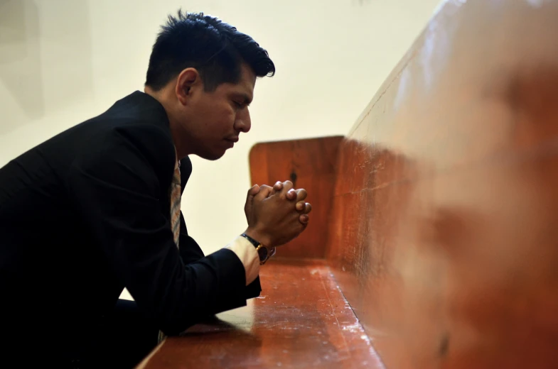 a man sitting and praying with his hands in the other direction