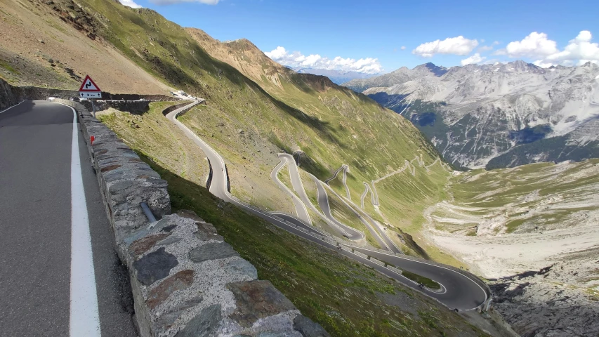 the roadway is winding down in between mountains