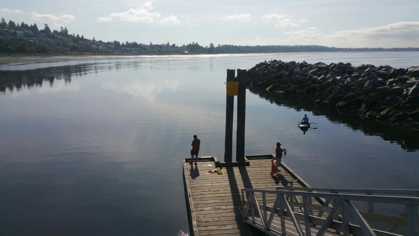 people standing on the dock near the water