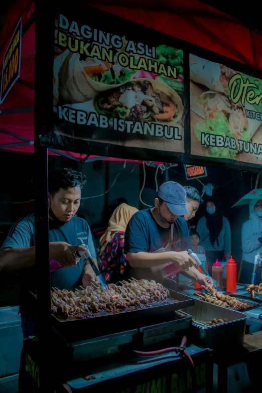 people stand near a street vendor selling various foods