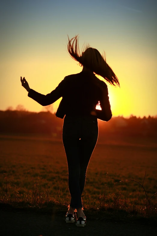 a person in silhouette walking towards a yellow sun