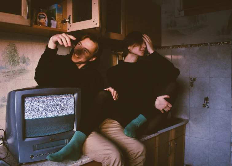 a man and woman sitting next to each other in a kitchen