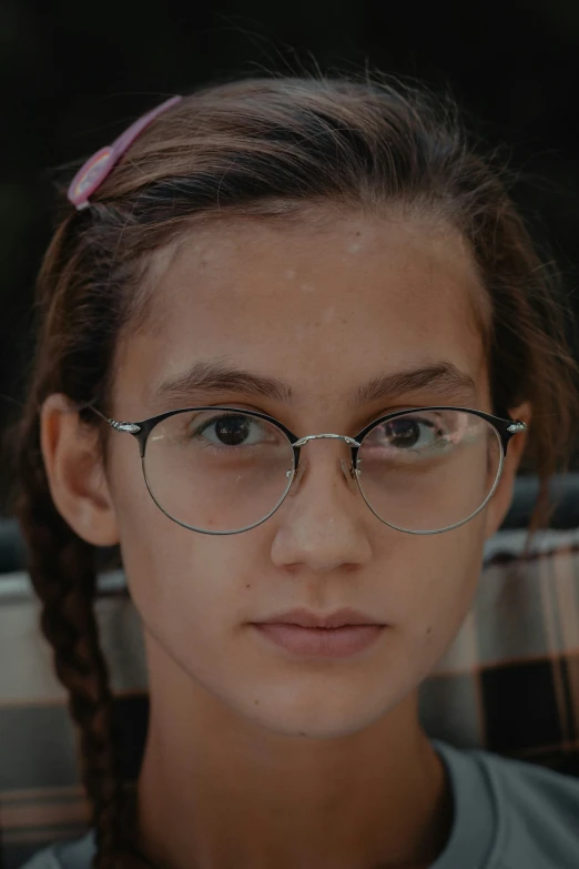 the young woman with glasses looks directly into the camera