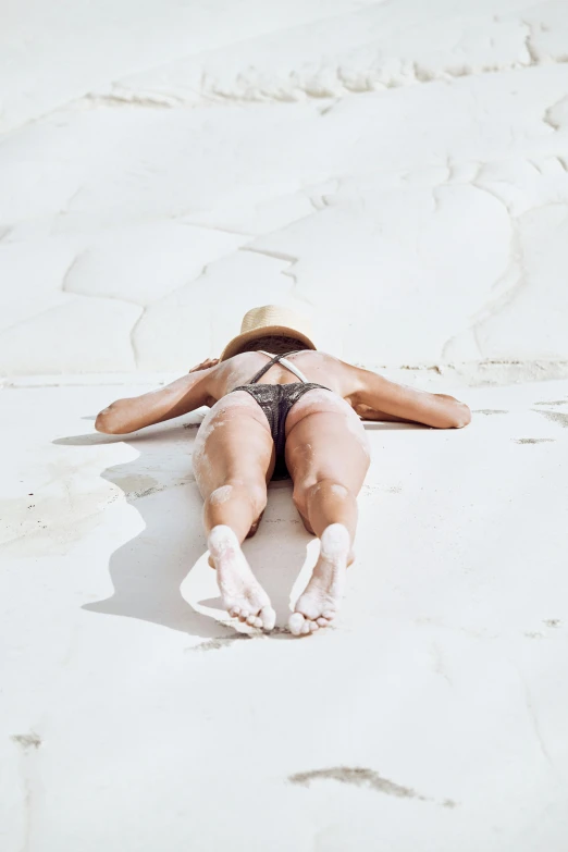 a woman lying on top of a sandy beach
