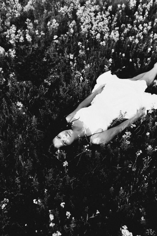 a person laying in a field of flowers with their hands extended