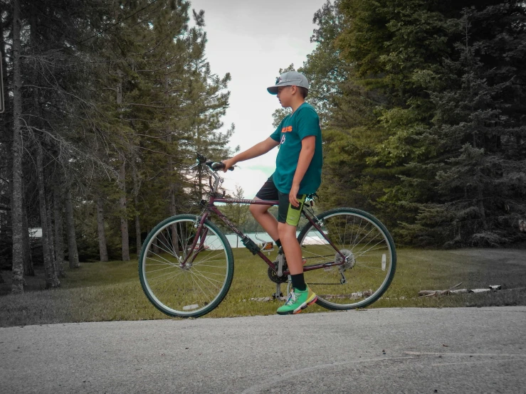 a man sitting on top of a bicycle next to a forest