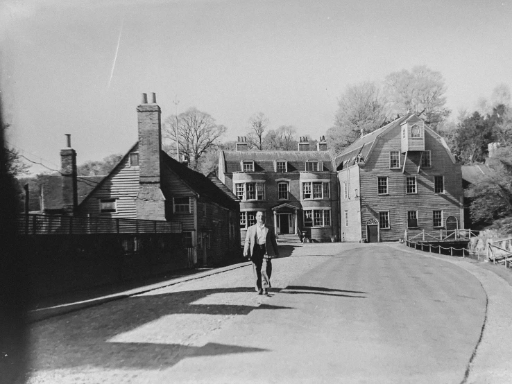 a man walking down a road in front of homes