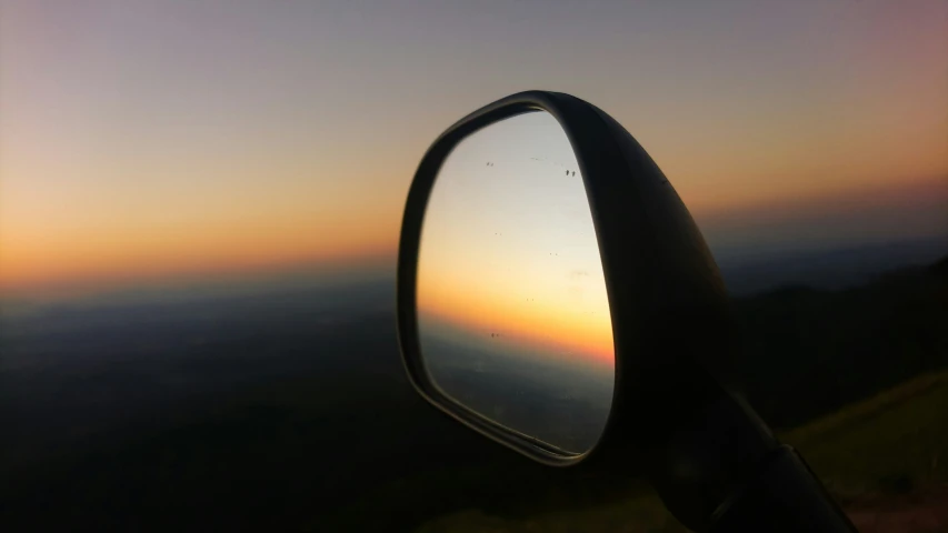 the sky is shown through the rear view mirror