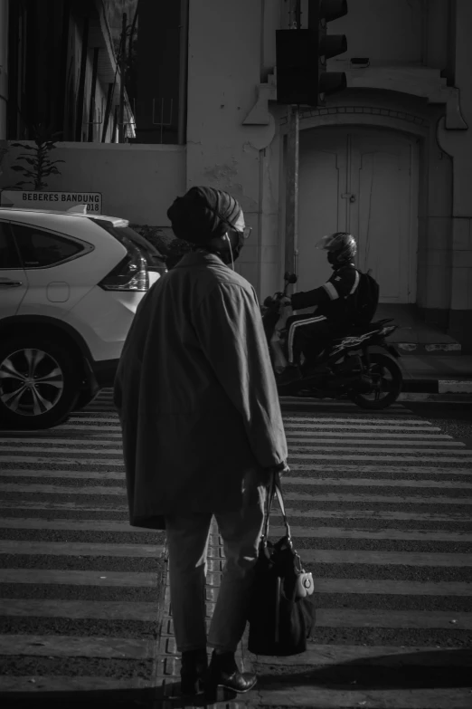 two people walking across the street in black and white