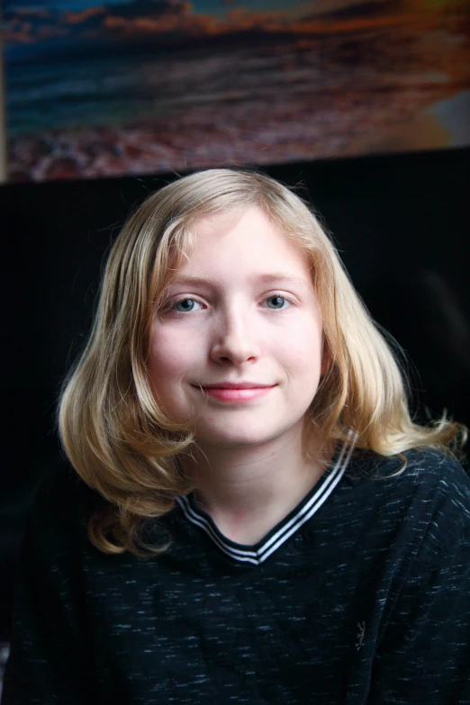 a blonde haired girl in black shirt with light blue eyes