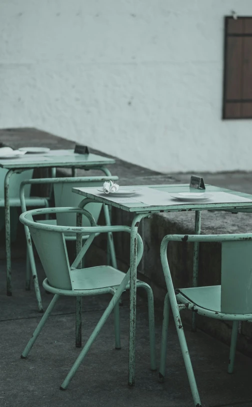 a couple of green tables sitting outside in the dirt