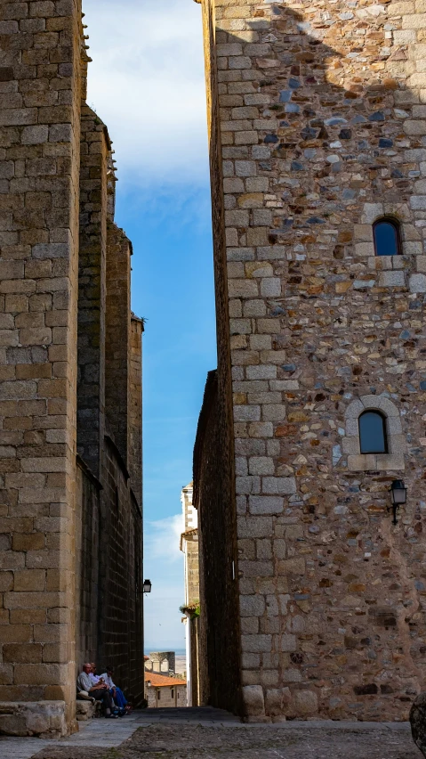 a small boy sitting in the middle of an alley way between two brick buildings