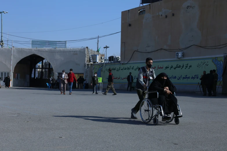 some people and one woman walking while another person on a wheel chair