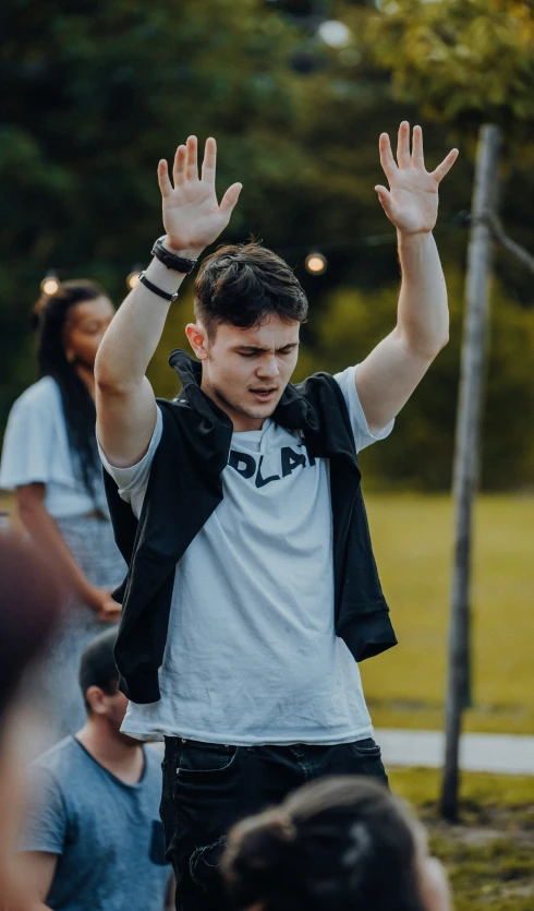 a man in white shirt standing in a crowd with arms up