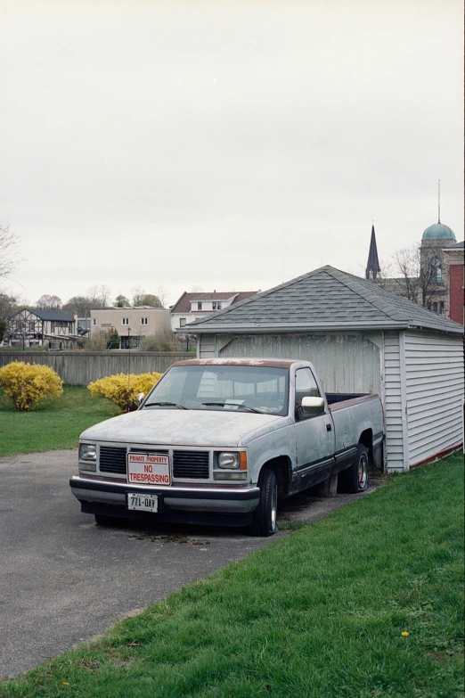 a pickup truck parked in a driveway in front of a small house