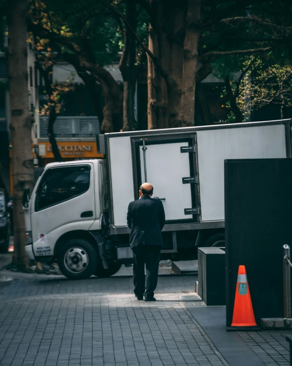 a man walks between two trucks next to a tree