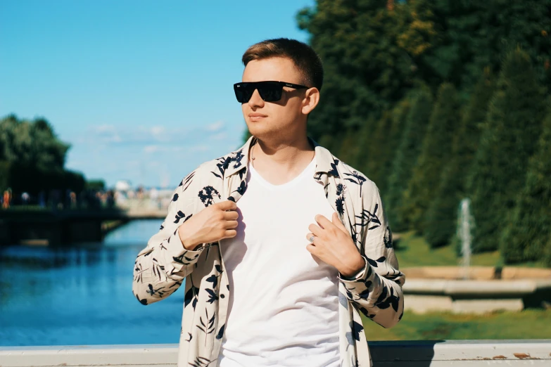 a man in sunglasses standing by water