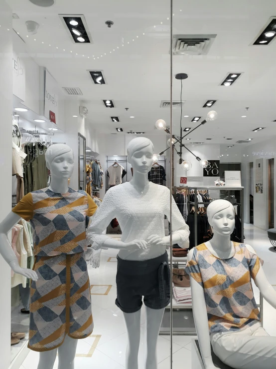two mannequins dressed in colorful clothing are behind the glass