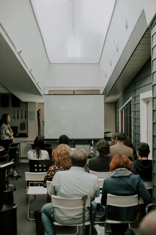 a classroom with students watching and listening to a man giving a lecture