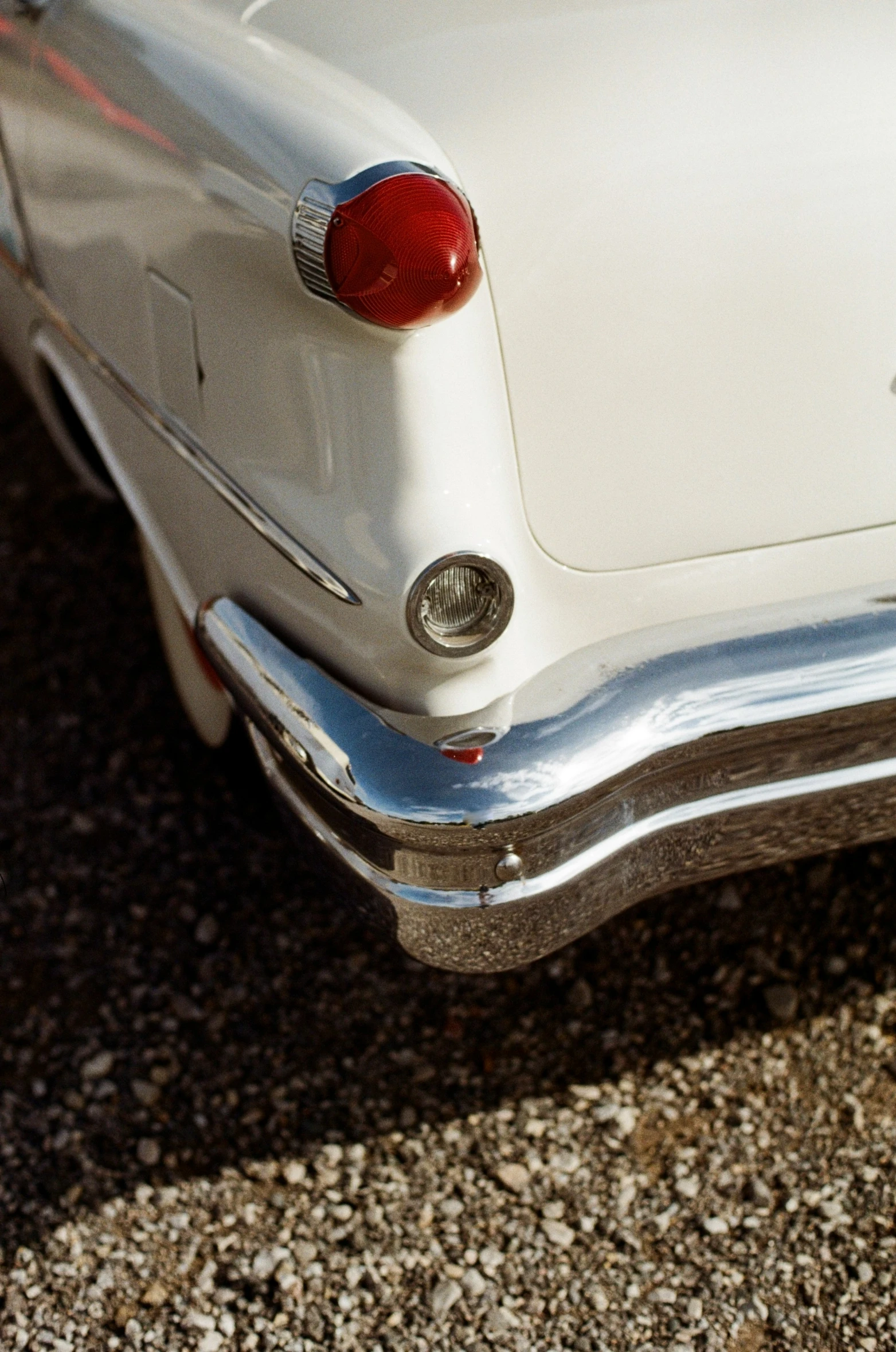 an old white car sitting on the side of the road