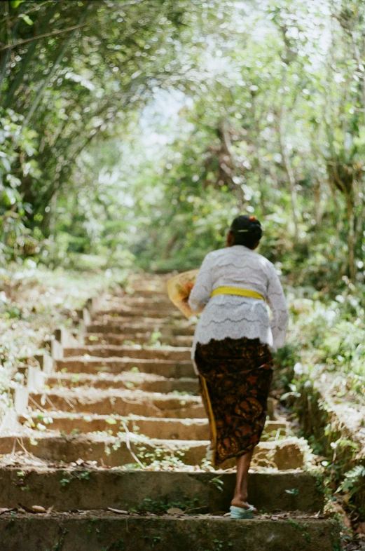 a woman walking down a stone stairs lined with vegetation