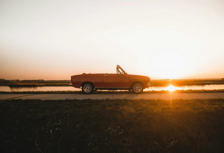 a truck is on the road and there is the sun behind it