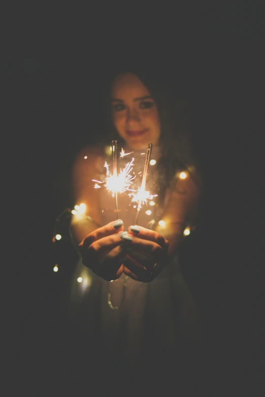 woman with sparkler in hand, dark background