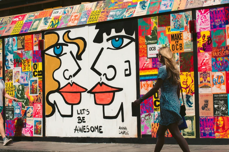 a girl walking past a building covered in colorful graffiti