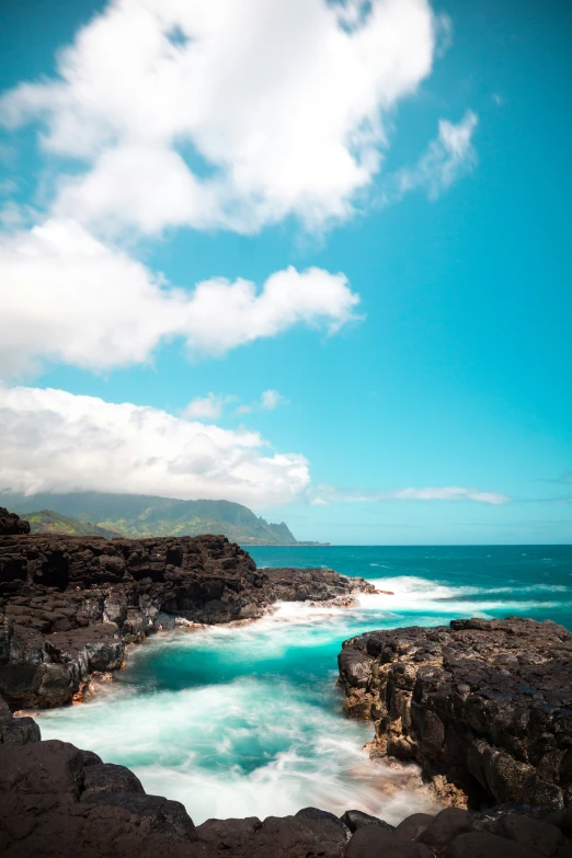 a rocky beach has turquoise water and clouds