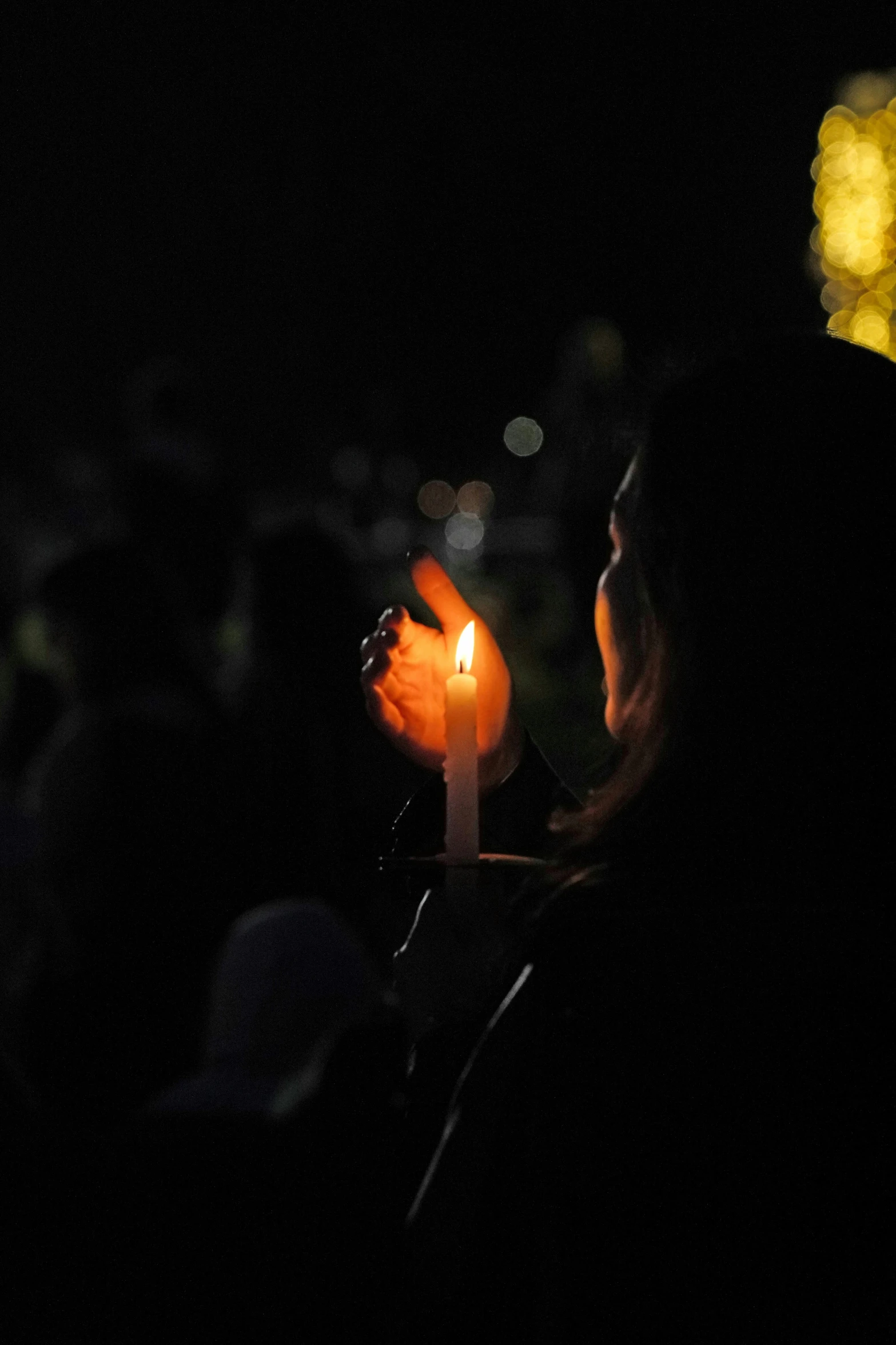 people standing with a candle lit in the dark