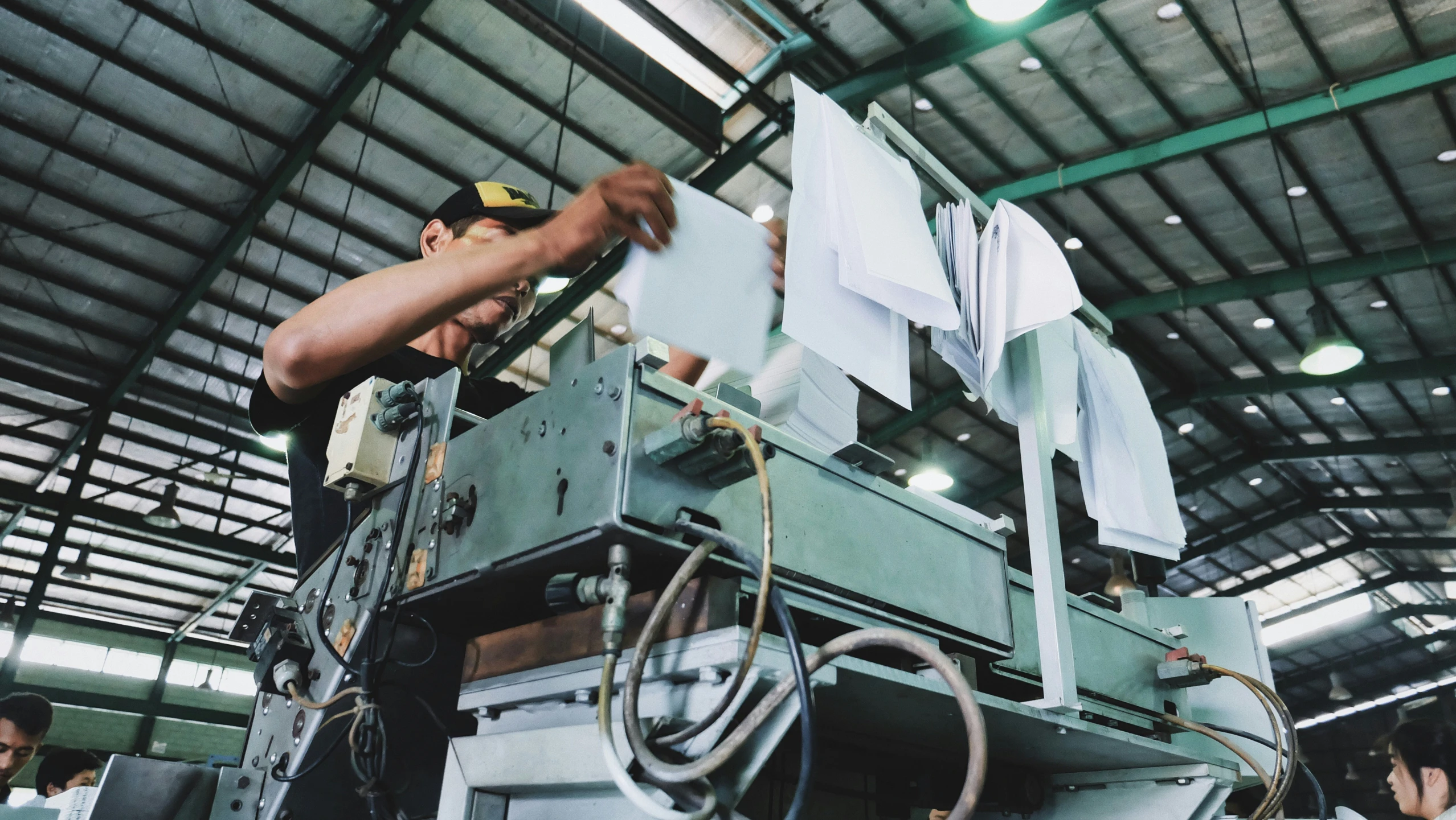 an older man works on a piece of paper in a machine shop