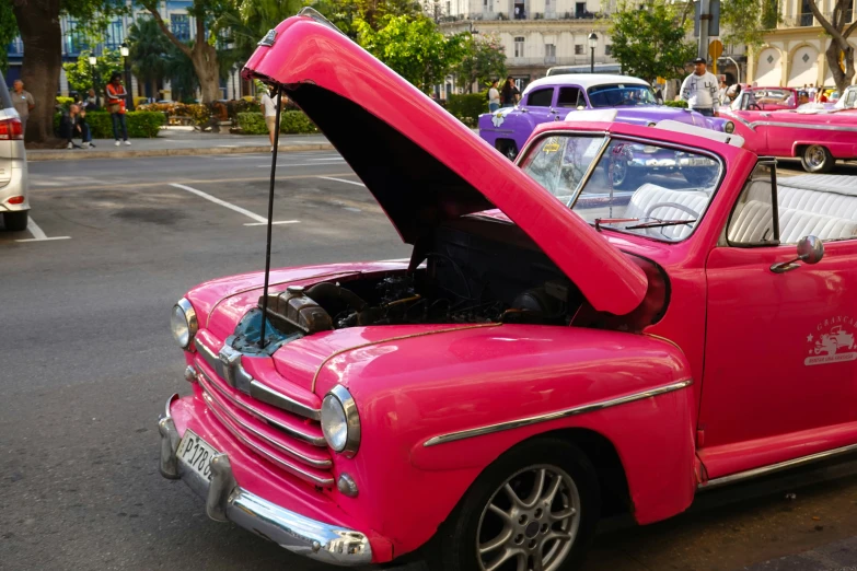 an old pink truck has a broken hood