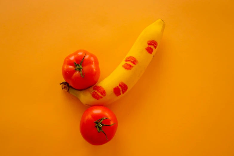 there are tomatoes and a banana on the yellow background