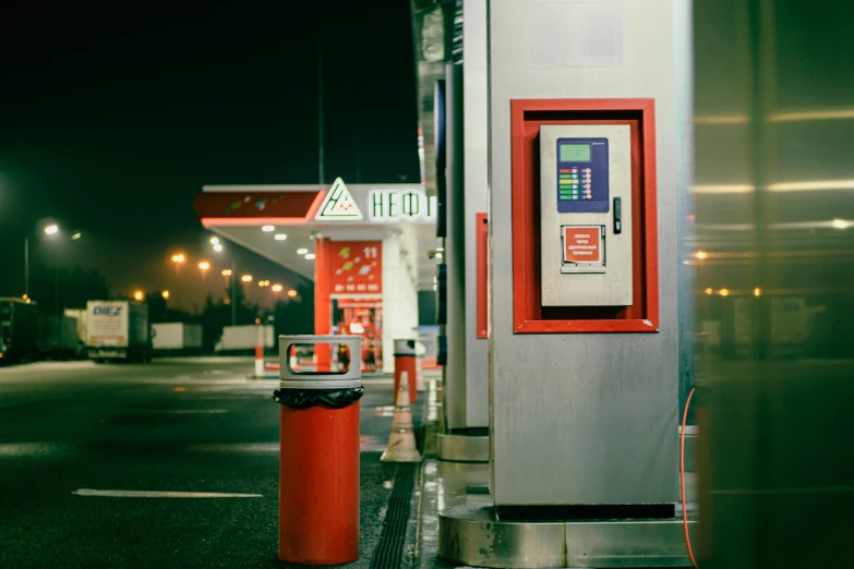 a large metallic gas pump sitting next to a red bin